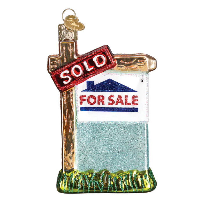 The Realty Sign Ornament by Old World Christmas (36203) features a house and green grass with a red SOLD banner—perfect as a unique homeownership gift or real estate keepsake.