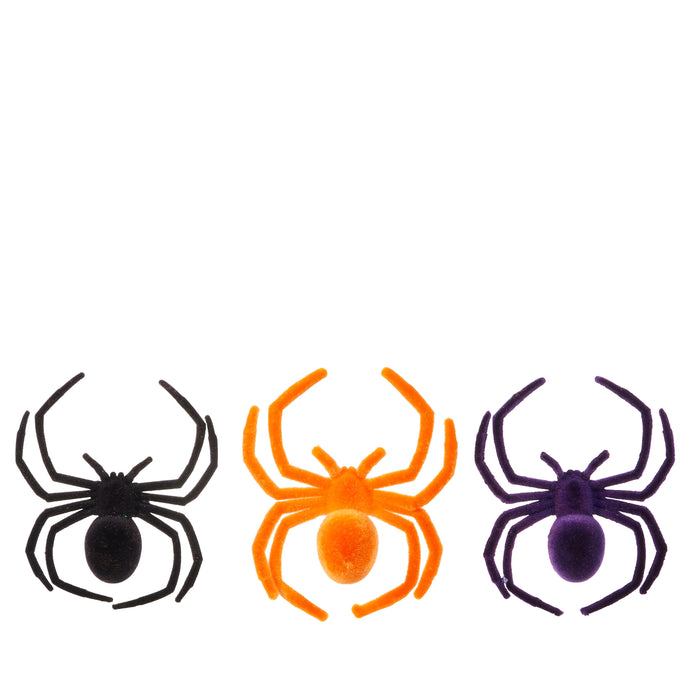 A 6.75" flocked spider in black, orange, or purple (product 4540845) is shown as a Halloween decoration on a white background. Three spiders are lined up side by side in black, orange, and purple from left to right.