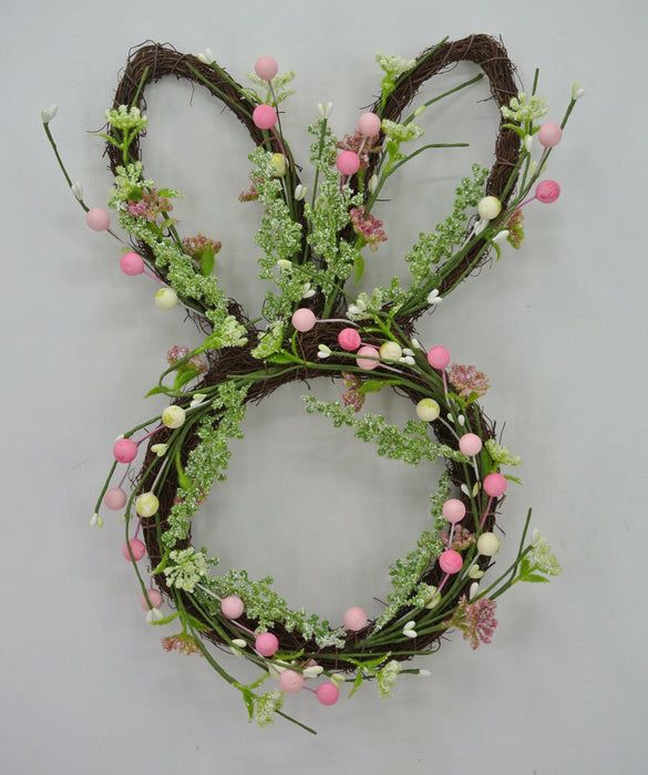 The 17 Easter Bunny Head 63764 is a whimsical wreath, ideal for Easter decor. Crafted from twigs, its adorned with pink and white eggs and green and white foliage on a plain background.
