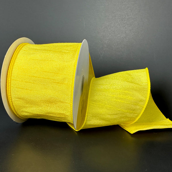 A partially unrolled spool of 2.5X10Y Daffodil Faux Dupioni Ribbon 72434-40-22, featuring a shiny texture and wired edge, is neatly wound around a cylindrical cardboard core against a dark background.