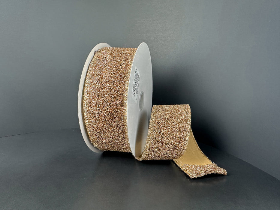 A large roll of 1.5X10Y Toffee-Black Fuzzy Metallic Ribbon (73566-09-35) is displayed on a white spool, with part of the strip unrolled and laying flat against a dark surface—resembling an industrial toffee ribbon.