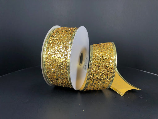 Two spools of the 1.5"X10Y Gold Super Glitter Ribbon shimmer against a dark background. One spool is partially unrolled, revealing its sparkling surface. These craft supplies feature white centers and a decorative scalloped edge.