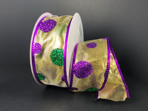 The 1.5X10Y Mardi Gras Glitter Dots/Gold Ribbon 75244-09-15, with its sheer gold base and glittery purple and green polka dots, is partially unwound against a dark background. The edges feature shiny purple trim, adding elegance to this wired ribbon masterpiece.