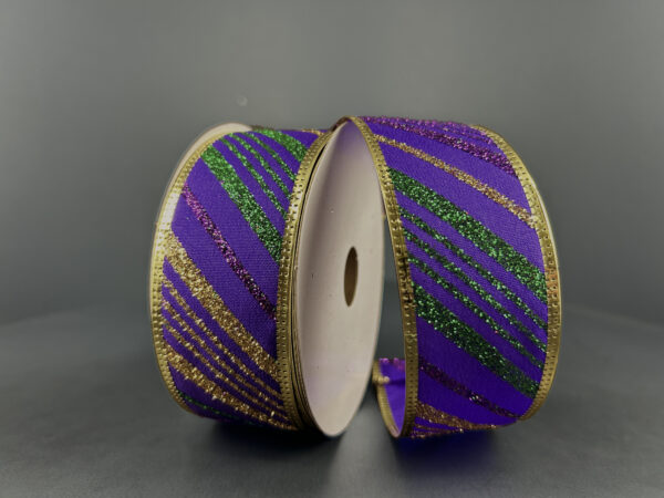 Two spools of 1.5X10Y Purple Satin/Gold-Emerald Glitter Diagonal Stripe Ribbon (76465-09-11) with sparkling gold edges are displayed upright against a plain dark background.