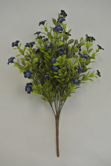 The 16 Blue Filler Bush 9 Stems 85152-BL features artificial green leaves and small dark blue flowers on brown stems, set against a plain light gray background.