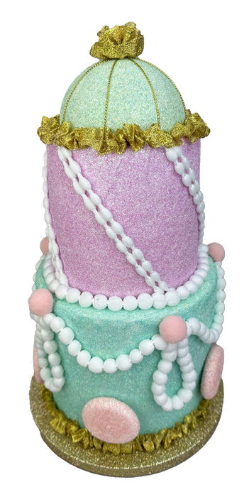 The 13" by 7.5" Pastel Three Tier Cake 86090PASTEL features mint green and pink tiers, gold trim, white pearl garlands, and pink accents for an ornate, whimsical look with charming pastel decoration.