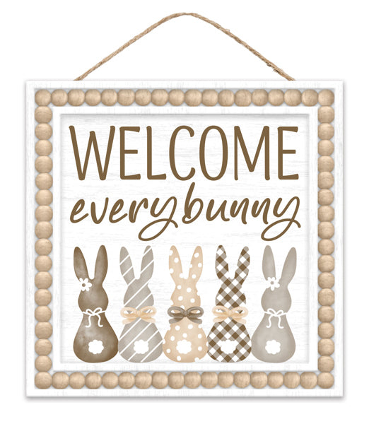 The 10SQ Welcome Every Bunny Sign (AP737882) features five patterned bunny silhouettes in neutral tones, each adorned with a bow. Playful script greets you, and a wooden bead border completes this charming MDF decor piece for your home.