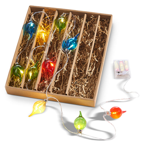 A 6-foot Lighted Multicolored Shiny Kismet Garland L4320902, featuring vibrant, teardrop-shaped string lights in red, blue, yellow, and green. It comes neatly arranged with shredded paper padding and includes a conveniently visible battery pack outside the box.