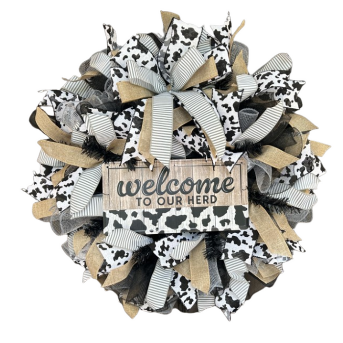 The Welcome To Our Herd Completed Wreath features black, white, and burlap cow-print ribbons with a wooden sign reading welcome TO OUR HERD, ideal for DIY fans or adding rustic charm to your space.