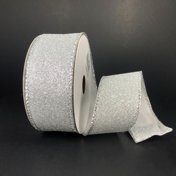 A partially unspooled roll of 1.5X10Y Silver All Flat Glitter Ribbon (X820609-16) with decorative edge is displayed against a plain black background.