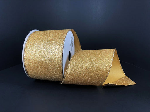 A 2.5X10Y Gold All Flat Glitter ribbon (X820640-15) is partially unspooled and displayed against a plain, dark background.