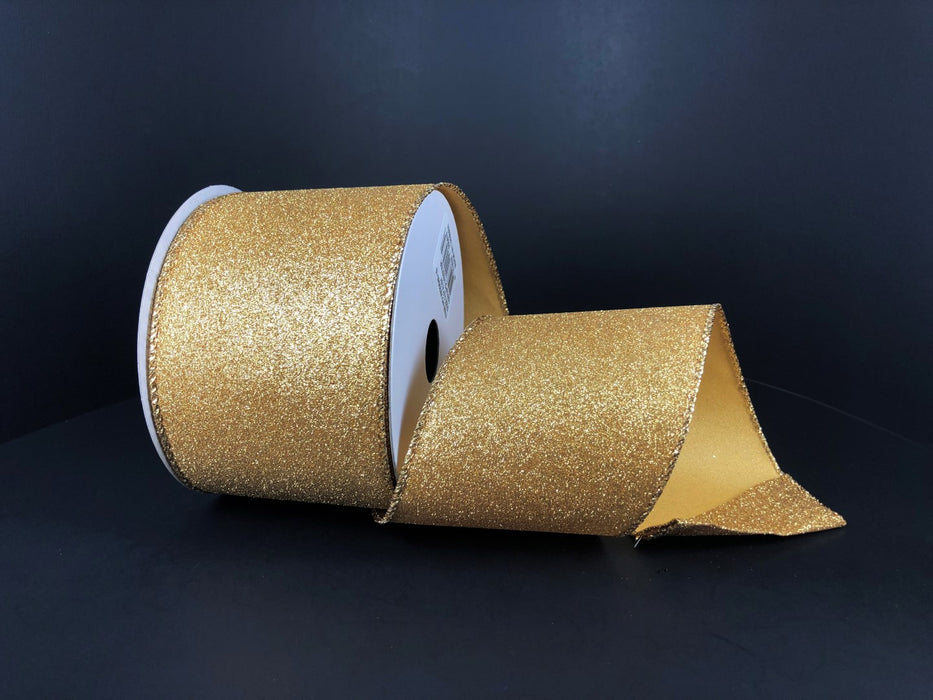 A 2.5X10Y Gold All Flat Glitter ribbon (X820640-15) is partially unspooled and displayed against a plain, dark background.