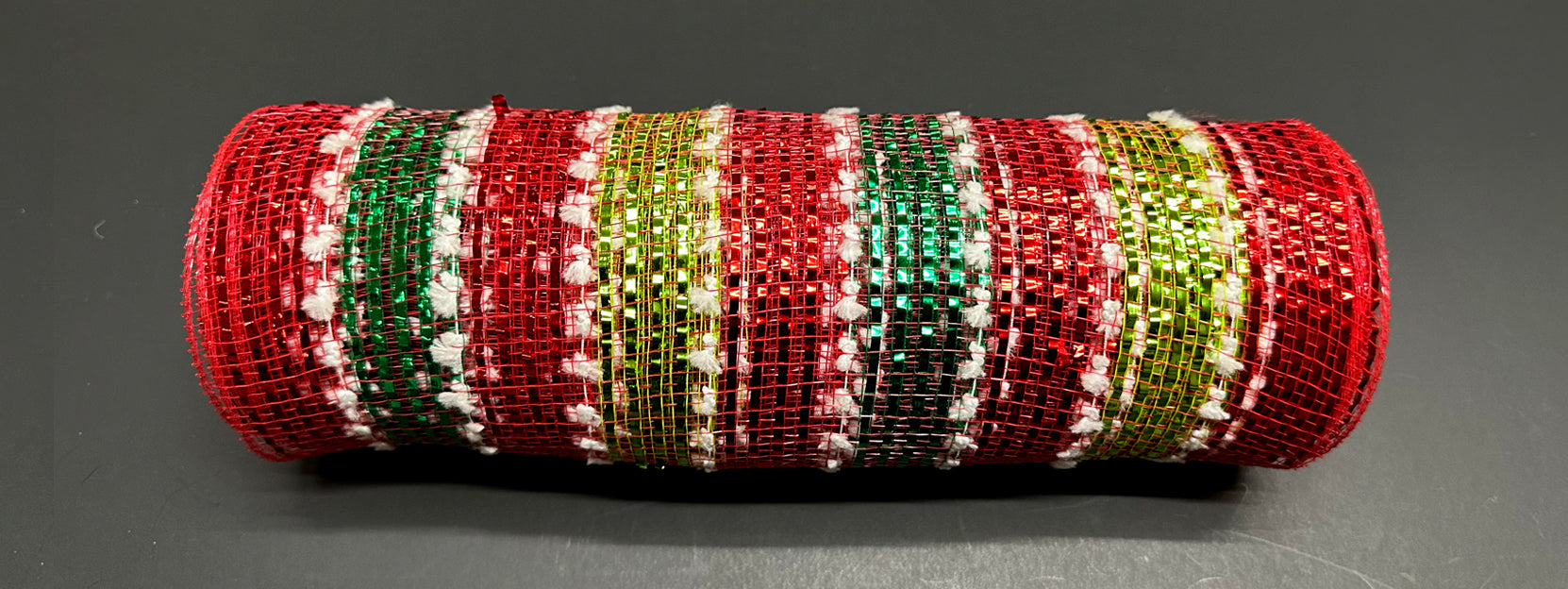 The 10X10Y Red-Lime-Emerald-Snowball Metallic Striped Mesh, model XB236210-12, features festive red, lime, and gold stripes with white accents. Displayed coiled on a dark surface, it gleams with holiday charm.