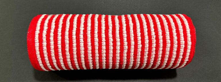 The 10X10Y Red-White All Snow Fuzz Stripe Mesh (XB253810-13) features red and white horizontal stripes and a textured, cylindrical design, shown against a dark gray background.
