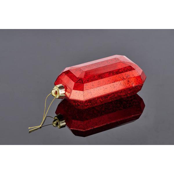 The 7 x 4 Red Rectangular Faceted Gem Ornament XJ551524, featuring a gold cap and hanging string, rests on a glossy black surface that reflects its vibrant color.