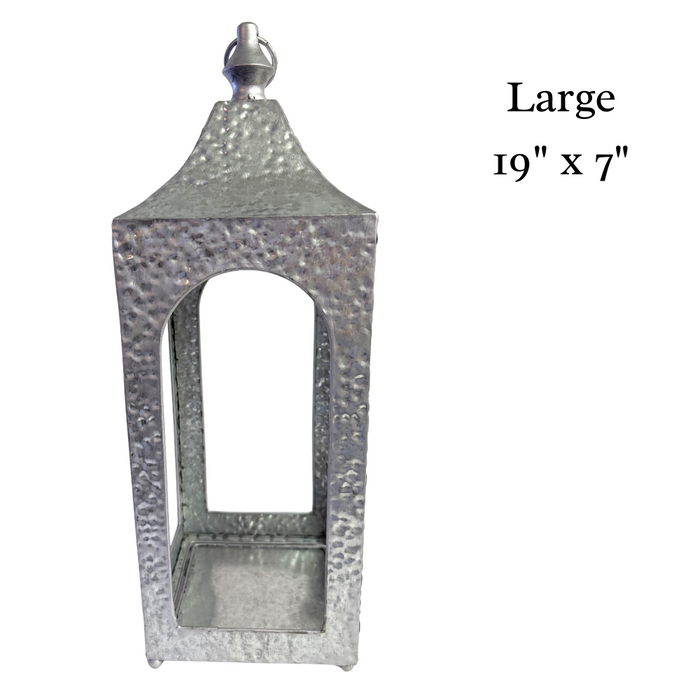 A set of two hammered silver artisan lanterns, sized 19 x 7 and 16 x 5, each with a rectangular design, textured surface, and open windows. Product: Hammered Silver Lantern Set 570600AB.