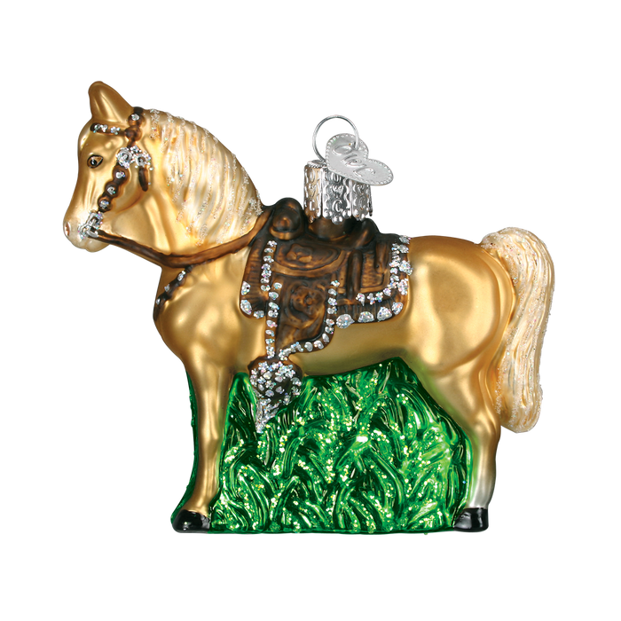 The Western Horse Ornament by Old World Christmas (12176) features a golden horse with a brown saddle, silver accents, a silver hanging loop, and stands on green grass—an ideal cowboy gift.