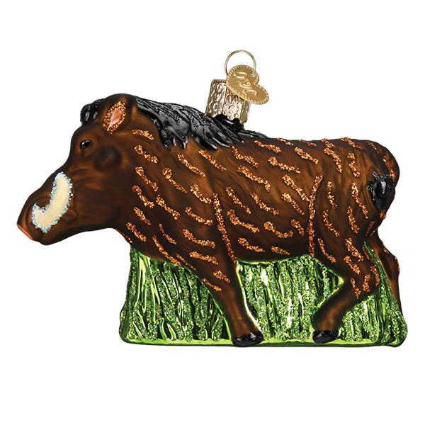 The Warthog Old World Christmas Ornament 12574 is a hand-painted glass piece with brown fur, orange accents, black hooves, green grass base, and a gold cap for hanging.