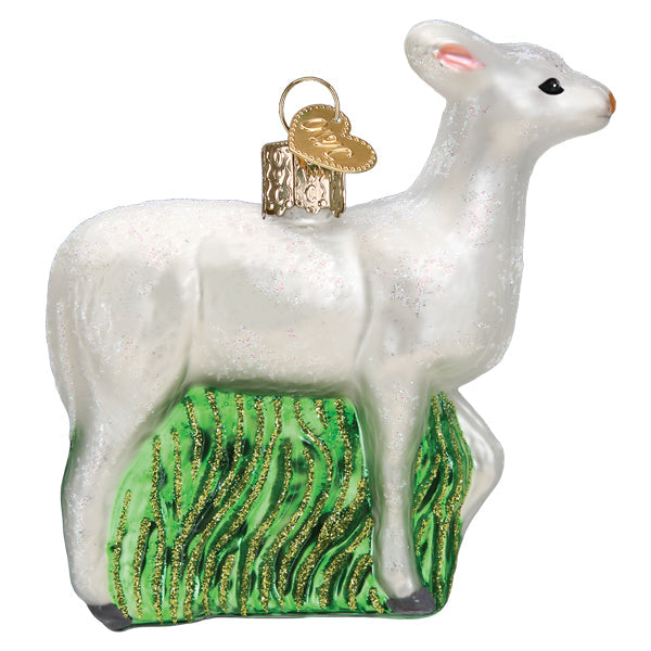 The Seneca White Deer Ornament by Old World Christmas (12605) features black eyes and nose, a gold hanging cap, and stands on glittery green grass, beautifully capturing the spirit of Seneca County, New York.