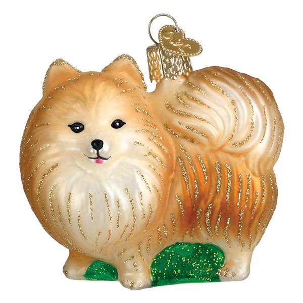 The Standing Pomeranian Ornament, from Old World Christmas (product number 12622), is shaped like a fluffy Pomeranian dog, highlighting its royal breed status. It is decorated with golden glitter and has a shiny gold top for hanging, all set on a small green patch.