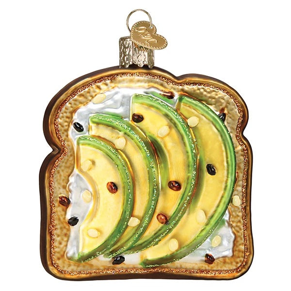 The Avocado Toast Old World Christmas Ornament 32442 is a decorative ornament shaped like avocado toast with cream cheese, featuring a gold hanging loop—a playful tribute to the popular food trend.