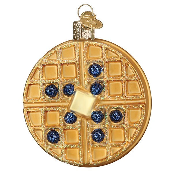 The Waffle Old World Christmas Ornament 32444 is a round tree decoration shaped like a Belgian waffle with butter, six sparkly blue berries, and gold glitter accents—a festive breakfast treat for your holiday décor.