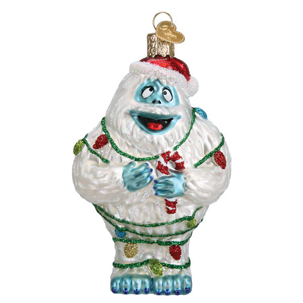 The Bumble Ornament by Old World Christmas (#44203) features the smiling Abominable Snow Monster from Rudolph, wearing a Santa hat and wrapped in colorful holiday lights.