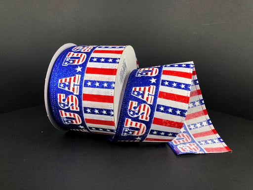 The 2.5X10Y Linen Flag USA/Stars-Stripes Ribbon (45323-40-74) features a red, white, and blue patriotic stars and stripes USA design, shown on a spool against a plain black background.