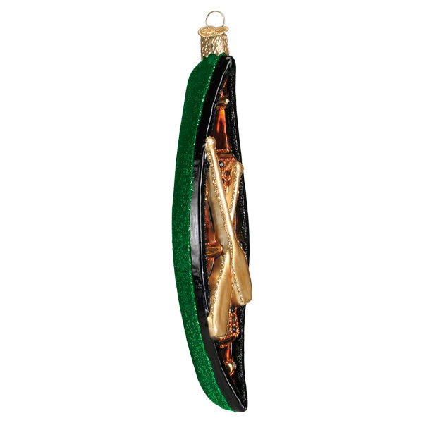 The Green Canoe Ornament by Old World Christmas (model 46111) is ideal for outdoor recreational enthusiasts, boasting a shiny finish and the classic shape of a wooden canoe. It includes two gold oars inside and features a top loop for easy hanging, making it a charming addition to your Christmas tree.