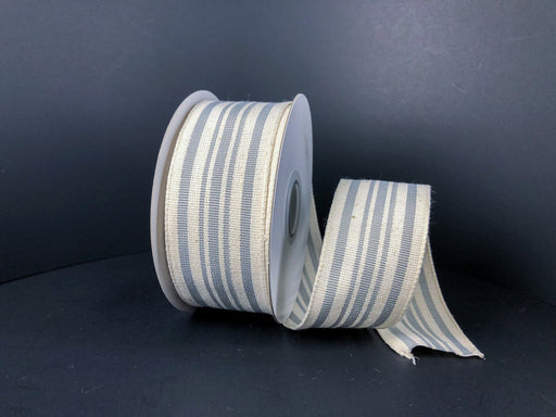 An Ivory/Gray Woven French Stripes ribbon, 1.5X10Y (Product: 6700109-51), is partly unraveled on a dark surface with a shadowy backdrop.