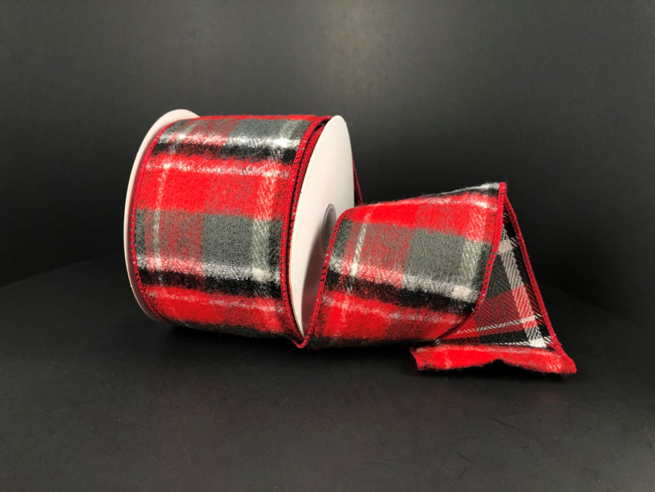 A roll of Brushed Red-White-Green-Black Plaid ribbon (2.5x10Y) lies partially unspooled against a dark backdrop, featuring neatly finished edges that enhance its elegant design.