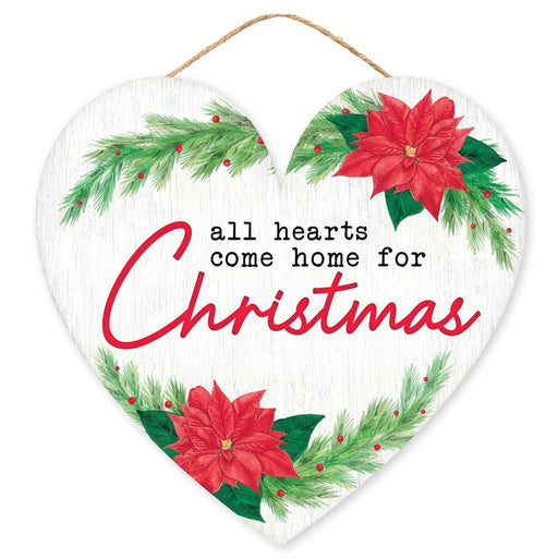 The 12Lx11.5H MDF Hearts Come Home Sign (AP7246) features a heart shape, green pine, red poinsettias, and all hearts come home for Christmas in black/red on white/red/green MDF/paper.