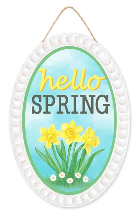 The 13Hx9L Hello Spring Oval Sign (AP7261) is made of MDF/paper with a white border, featuring yellow daffodils and hello SPRING text in yellow and black on an ice blue background. It includes a twine loop for easy hanging.