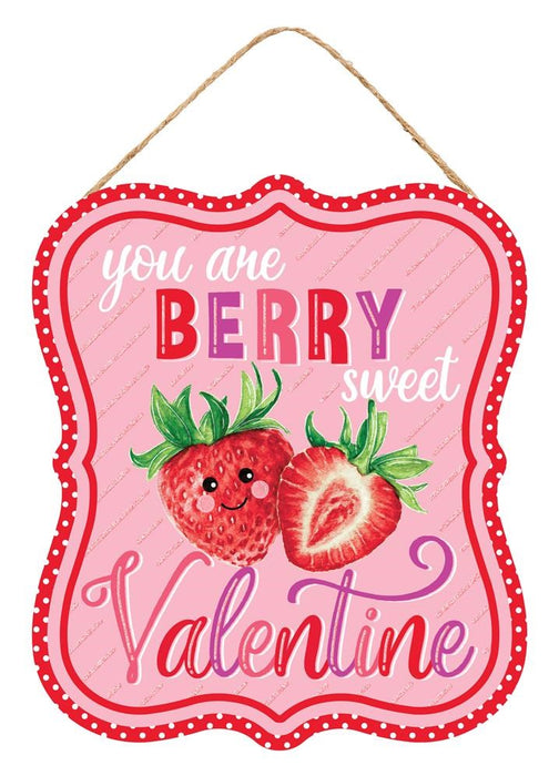 The 10.5Hx9L You Are Berry Sweet Valentine sign (AP7833) features a smiling and sliced strawberry on a pink backdrop. The phrase You are BERRY sweet Valentine is written in bold red, white, and purple fonts and bordered with scalloped red edges and white polka dots.