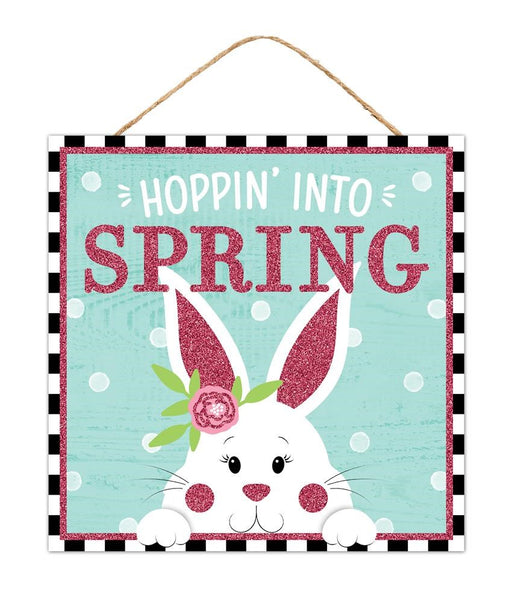 The 10Sq Hoppin Into Spring/Bunny Glitter sign (AP8992) features a cute white bunny with a pink flower against a teal polka-dot background. Hoppin Into Spring sparkles in pink glittery letters, and its hung by a sturdy rope for charming MDF spring decor.