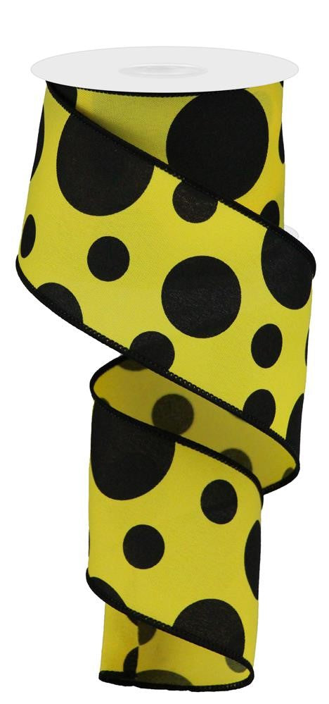 The 2.5X10Yd Giant Three Size Dot/Pg Fabric Yellow/Black RGA194329 ribbon, featuring a yellow background with large black polka dots, is partially unwound to display its vibrant pattern.