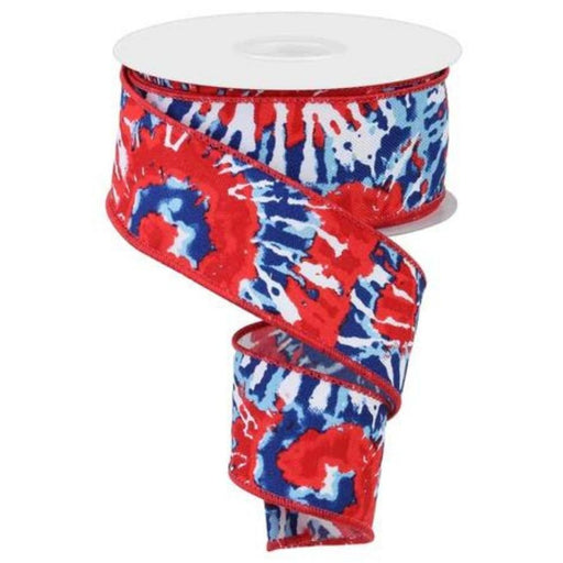 The 1.5X10YD spool of RGE1234A1 ribbon features a vibrant red, white, and blue tie-dye pattern with a mesmerizing spiraling design as it partially unravels.