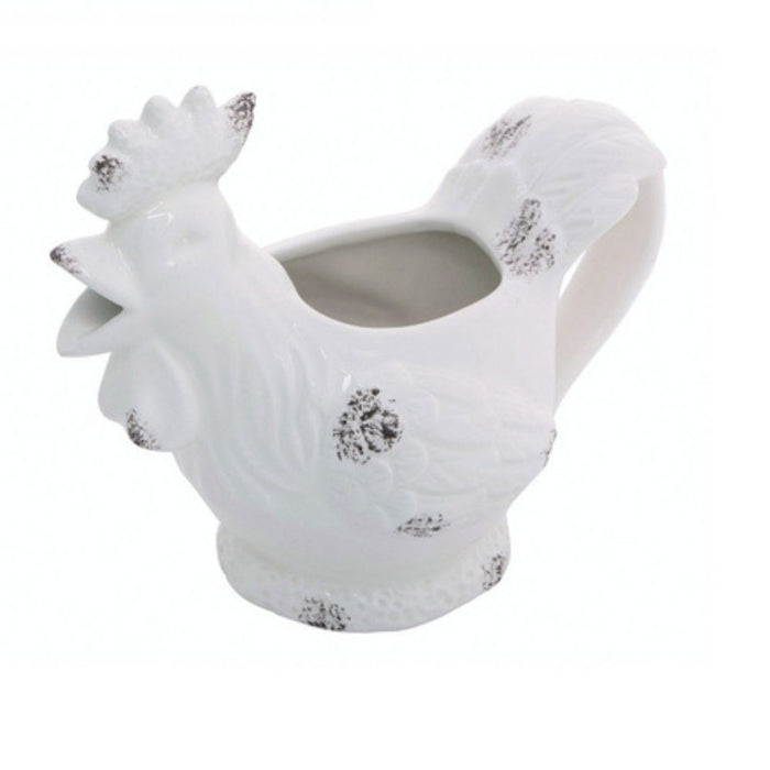 The Farm Animal Creamer Assorted A2536 is a white ceramic rooster-shaped pitcher with embossed feather details and brown speckles on the beak, wings, and tail—a charming addition to your table.