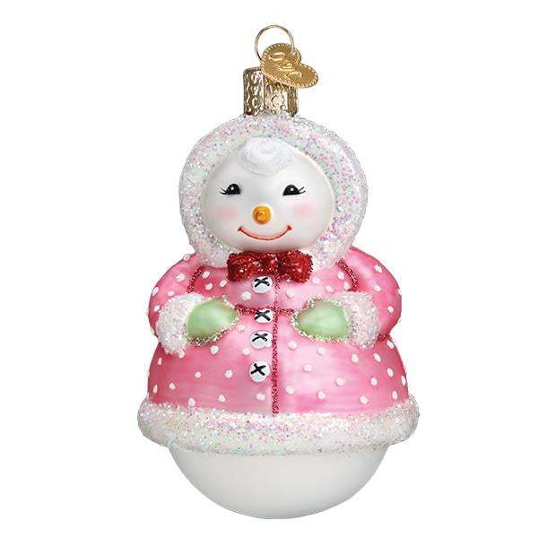The Jolly Snowlady 10231 Old World Christmas Ornament features a snowman in a pink polka-dotted coat with white trim, green mittens, a red bow tie, and a smiling face with a carrot nose.