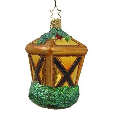 The Warm Welcome Lantern Christmas Ornament by Inge-Glas of Germany (1-062-04) features mouth blown glass in gold, brown, and yellow panels with green glitter, holly on top, and hangs from a star-shaped hook.