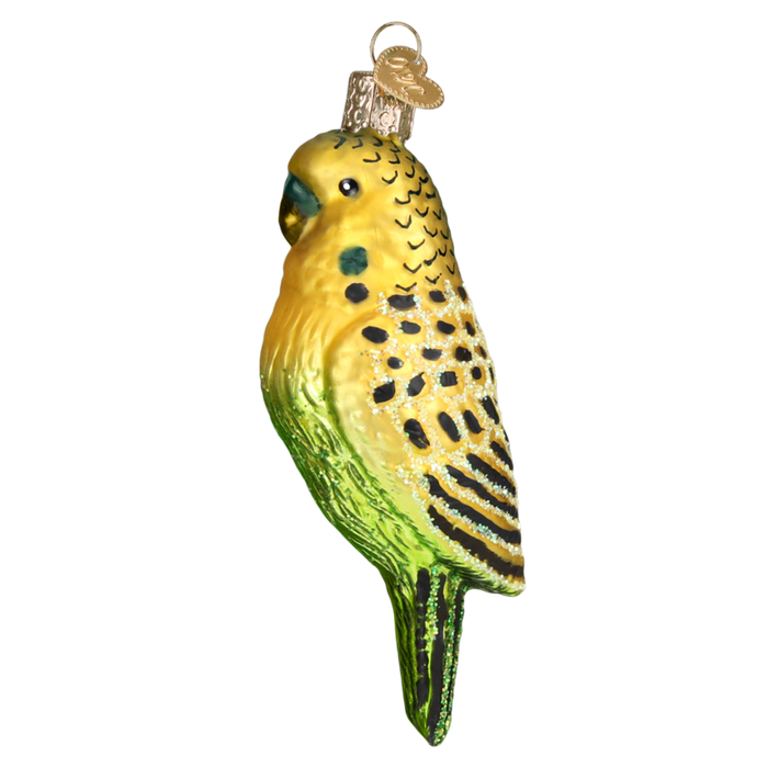 The Miniature Parakeet 16123 Old World Christmas Ornament is crafted from mouth-blown glass, featuring a yellow head and green body with intricately hand-painted black and yellow details. It's equipped with a gold cap for easy hanging, adding charm to any setting.
