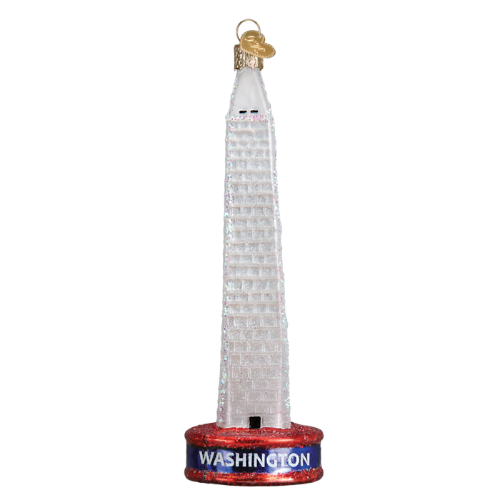 The Washington Monument 20093 Old World Christmas Ornament is a glass ornament with a red glittery base labeled “Washington” in white and a gold loop for easy hanging.