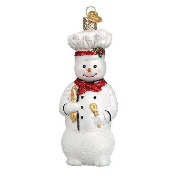 The Snowman Chef 24184 Old World Christmas Ornament is a hand-painted glass decoration featuring a smiling chef with a white hat, red scarf, baguette, spoon, and finished with a gold hanging loop.