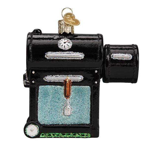The Smoker BBQ 32388 Old World Christmas Ornament is a shiny black hand-painted glass ornament featuring a glittery blue window, thermometer, silver spatula, and gold hanging loop, shown against a white background.