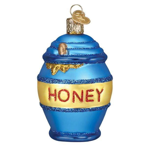 The Honey Pot 32391 Old World Christmas Ornament features hand-painted blue and yellow glass, "HONEY" in red glitter, gold detailing, and a gold cap with a hanging loop—an Old World Christmas collectible.