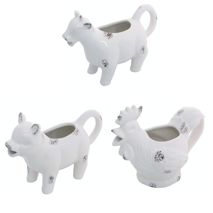 The Farm Animal Creamer Assorted A2536 set includes three white ceramic creamers shaped like a cow, pig, and rooster, each with a tail handle, mouth spout, and small brown spots for added charm.