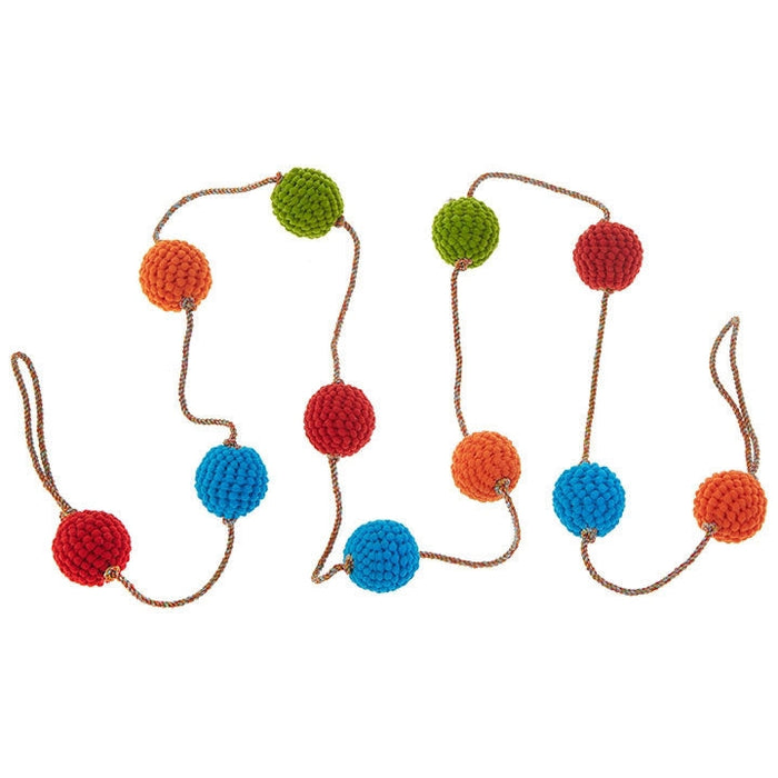 The RAZ Knitted Ball Garland showcases large, textured balls in vibrant red, orange, blue, and green on a brown twisted cord with end loops, arranged in waves against a white background.