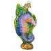 The Bright Seahorse Ornament by Old World Christmas (12655) is designed as a symbol of luck, crafted in colorful glass with striking purple and blue hues, green fins, and detailed glitter embellishments. It includes a decorative green seaweed backdrop with intricate golden accents, capturing a mystical meaning and enchanting allure.
