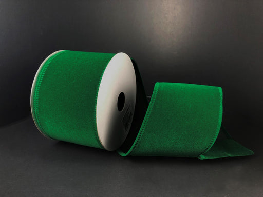 A 2.5x10y spool of Christmas Velvet (131840-17) in emerald green is partially unwound, revealing its white core against a dark background.