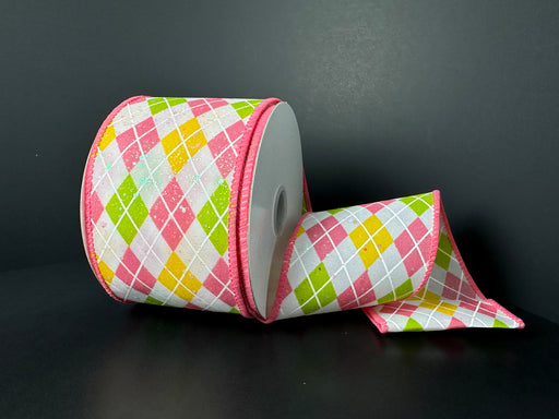 A 2.5X10Y White Iridescent Glitter Satin/Kiwi-Pink-Yellow Argyle Diamonds Ribbon features an argyle pattern in pink, green, yellow, and white with a sparkling finish. The wired edges are pink, and a section is unrolled on a dark background.